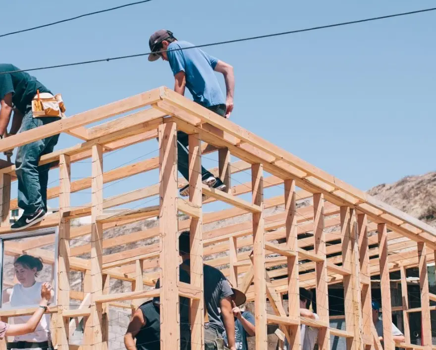 Construction crew framing the wooden roof structure of a new residential project by BlueSky Home Offer.